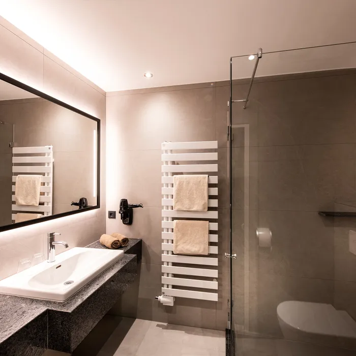 Moderno bagno d'hotel con doccia walk-in, lavabo sospeso e scaldasalviette